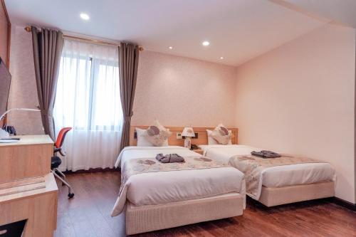 a hotel room with two beds and a television at MOMIZI Hotel HAI PHONG in Hai Phong