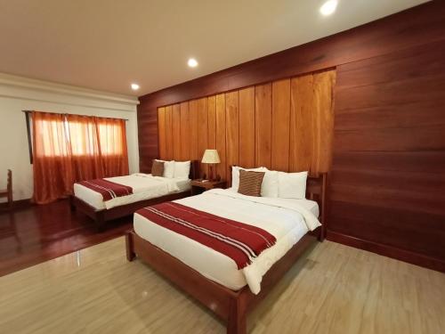 two beds in a hotel room with wooden walls at San Pedro Country Farm Resort and Event Center Inc in Cantilan