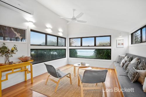 a living room with a couch and chairs and windows at The Lennoxhaus in Lennox Head