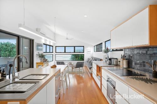 a kitchen with white counter tops and windows at The Lennoxhaus in Lennox Head