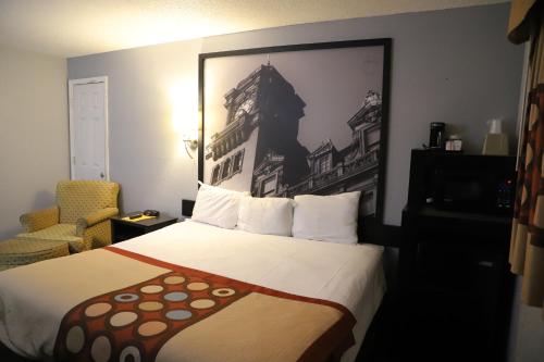 Super 8 by Wyndham Richmond Airport VA في ساندستون: غرفة فندق بسرير وصورة على الحائط