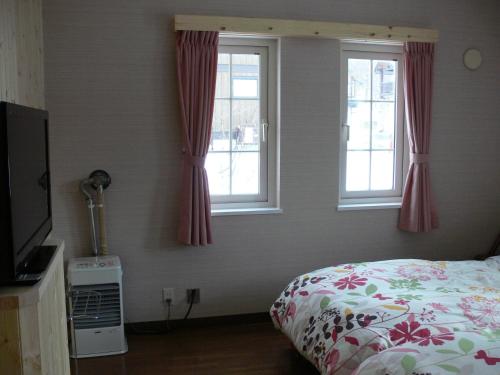 a bedroom with a bed and two windows at Pension Locomotion in Kutchan