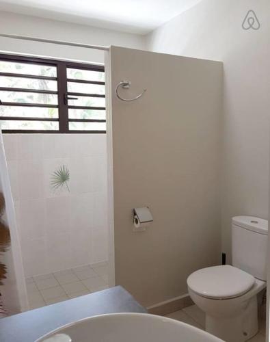 a white bathroom with a toilet and a shower at Villa Tiarenui in Maharepa