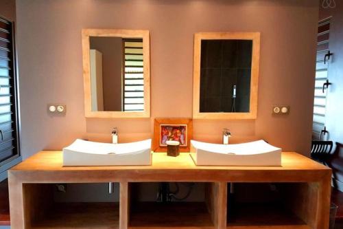 two sinks in a bathroom with two mirrors at Villa Meheana in Moorea
