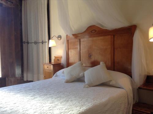 a bedroom with a white bed with a wooden headboard at Casa Rural Pico Espadan in Almedíjar