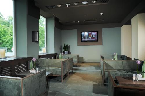 a waiting room with couches and a tv on the wall at Hotel Stadtpalais in Cologne