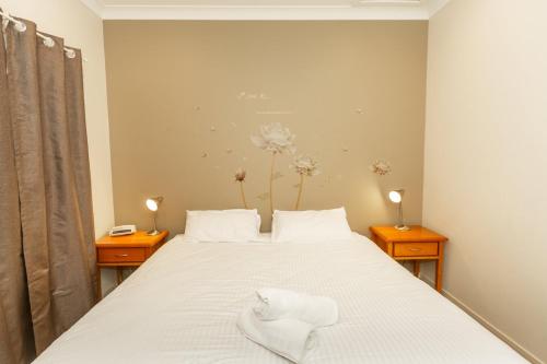 1 dormitorio con 1 cama blanca y 2 mesitas de noche en Cottage 20 - 3 Bedroom - Lake Hume Resort, en Albury