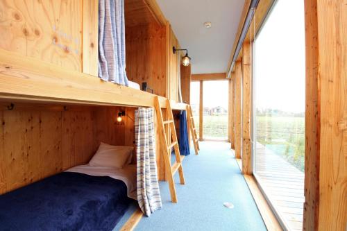 Etagenbett in einem Holzzimmer mit Fenster in der Unterkunft COCORETO The Guesthouse Daikon Island in Matsue