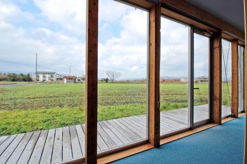 a room with a window looking out at a field at COCORETO The Guesthouse Daikon Island in Matsue