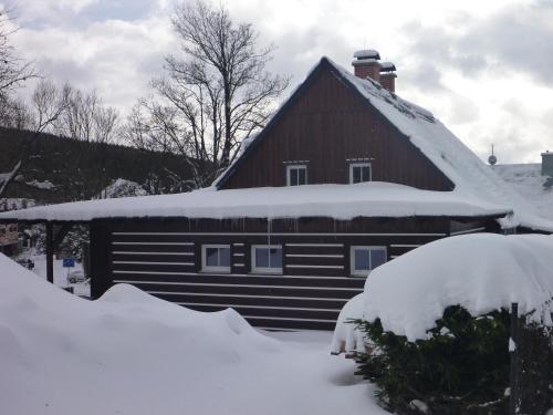 a house with snow on the roof of it at Chalupa Krkonoše in Cerny Dul