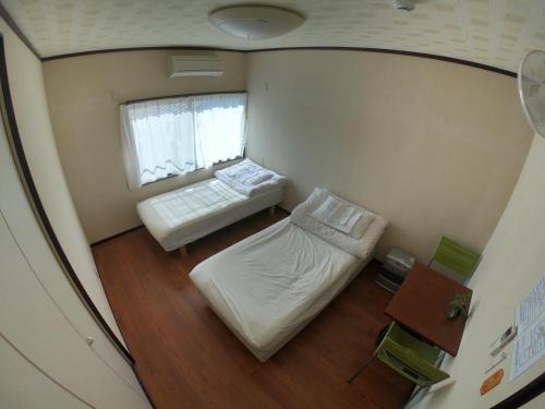 a small room with a bed and a window at Kumano Backpackers in Tanabe
