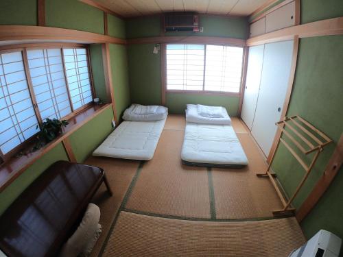a room with three beds in a room with windows at Kumano Backpackers in Tanabe