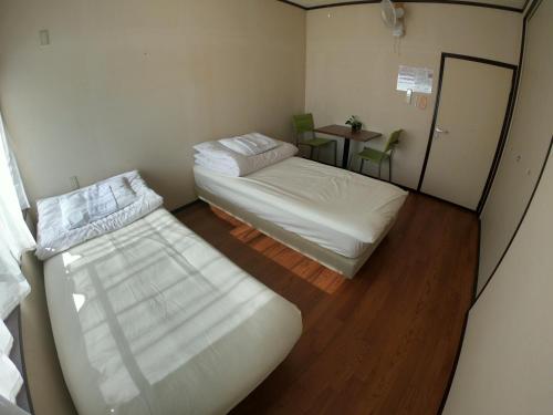 a small room with two beds and a table at Kumano Backpackers in Tanabe