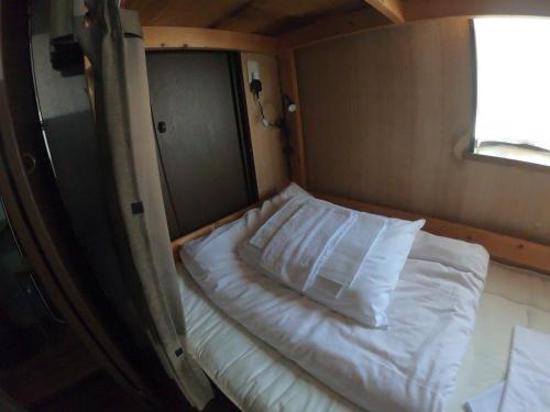 a bed in a small room with a window at Kumano Backpackers in Tanabe