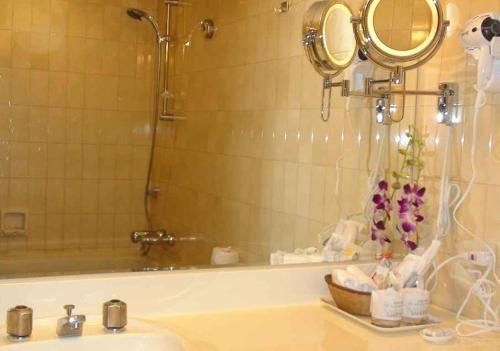 台南的住宿－首相大飯店，浴室配有水槽和带镜子的浴缸