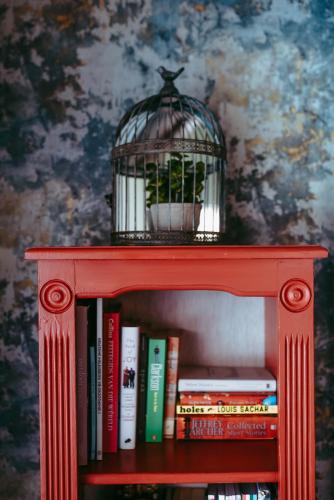 a red book shelf with a bird cage on top at Timeless Bloemfontein in Bloemfontein