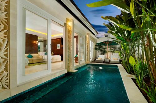 スミニャックにあるBajra Bali Villa Seminyakのリビングルーム付きのヴィラで、インフィニティプールが備わります。