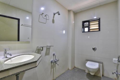 a bathroom with a sink and a toilet at Hotel Merit in Surat