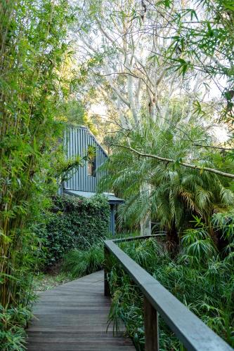 a wooden path through a garden with a bench at Empire Spa Retreat in Dunsborough