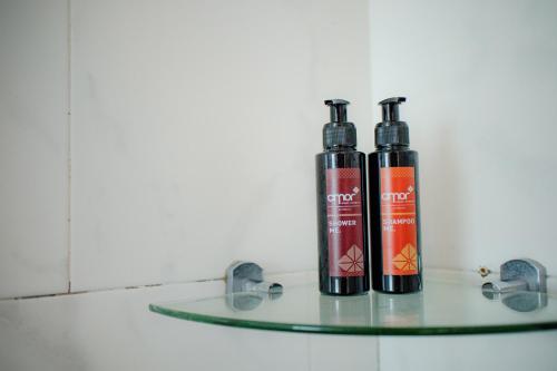 two bottles sitting on a glass shelf at Cmor by Recall Hotels SHA Extra Plus in Chiang Mai