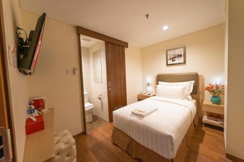 a hotel room with a bed and a bathroom at d'primahotel Airport Jakarta 2 in Tangerang