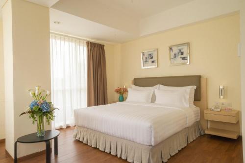 a bedroom with a large white bed and a window at d'primahotel Airport Jakarta 2 in Tangerang