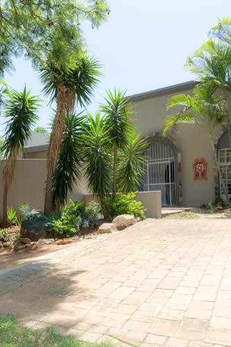 a house with palm trees in front of a driveway at Barberton BnB in Barberton