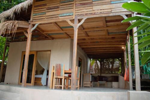 a house with a wooden roof with chairs and a table at Jati Village, Party Hostel and Bungalows in Gili Trawangan