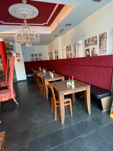 a dining room with tables and chairs and a red couch at CineHotel Maroni in Zirndorf
