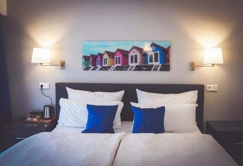 Schlafzimmer mit einem Bett mit blauen und weißen Kissen in der Unterkunft Hotel-Restaurant Osterather Hof in Meerbusch