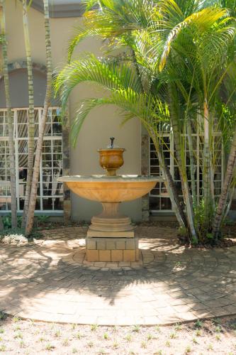 a fountain in front of a building with palm trees at Barberton BnB in Barberton