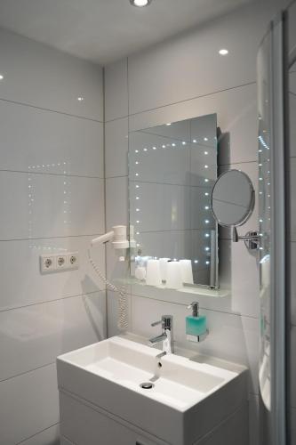 a white bathroom with a sink and a mirror at Hotel-Restaurant Osterather Hof in Meerbusch