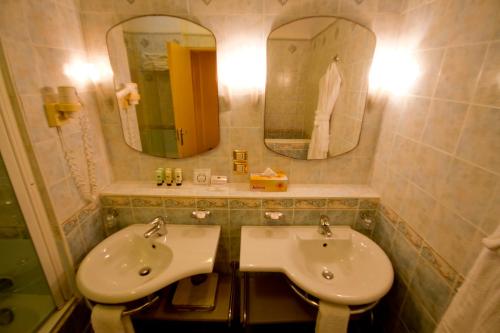 a bathroom with a sink and two mirrors at The Kairaba Beach Hotel in Kololi