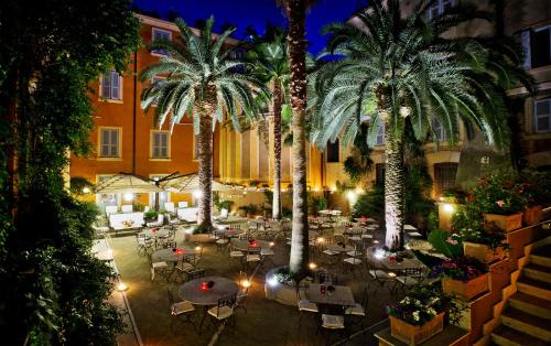 a courtyard with tables and palm trees at night at Hotel Ponte Sisto in Rome