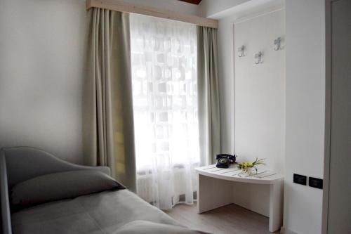 a bedroom with a bed and a window with a table at B&B Seventy Design in Dimaro