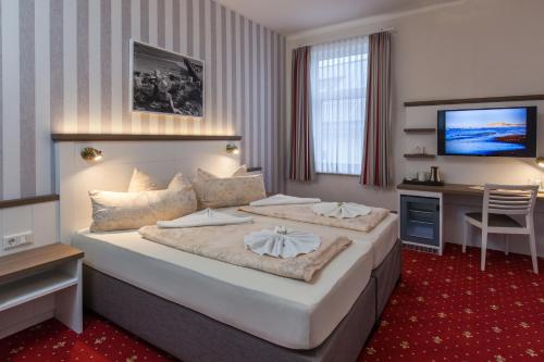 a hotel room with a large bed and a desk at Hotel Weisse Düne in Borkum