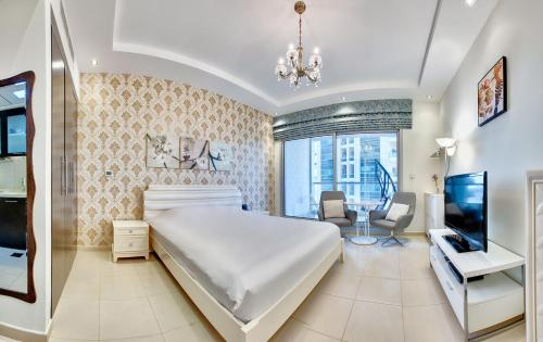 a bedroom with a large white bed and a television at Cute Dubai Marina Studio in Skyview Tower in Dubai