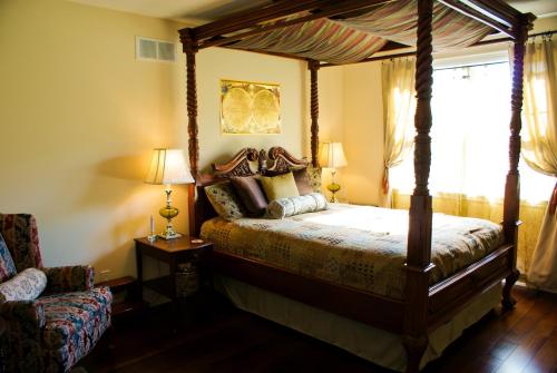 a bedroom with a canopy bed and a chair at Gatekeeper's Retreat in Niagara on the Lake