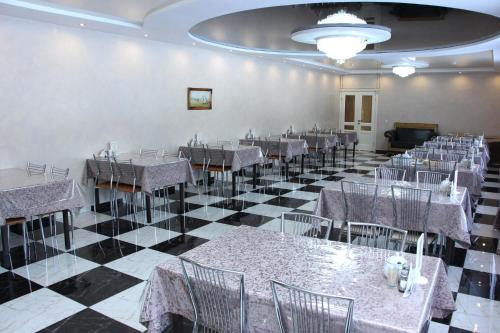 a dining room with tables and chairs on a checkered floor at Zhaylau Hotel in Shchūchīnsk