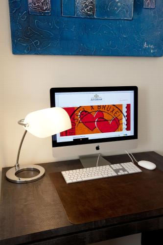 a computer monitor and a lamp on a desk at Art de Sejour - B&B in Brussels