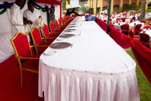 a long white table with red chairs and people at The Kairaba Beach Hotel in Kololi