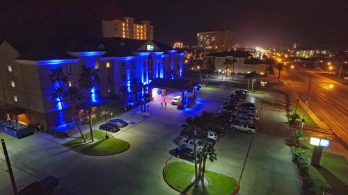 a city at night with cars parked in a parking lot at Holiday Inn Express Hotel and Suites South Padre Island by IHG in South Padre Island