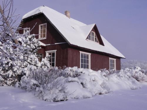 a red barn with snow on the roof at Järve Talu Puhkemaja in Otepää