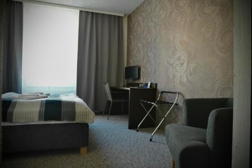 a bedroom with a bed and a desk and a window at Promohotel Slavie in Cheb