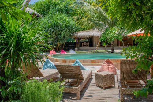 a resort with a swimming pool with chairs and a table at Jati Village, Party Hostel and Bungalows in Gili Trawangan