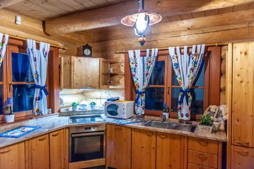 a kitchen with wooden cabinets and a sink and windows at Chata na brehu Liptovskej Mary in Bobrovník