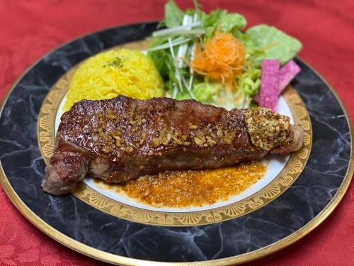 a plate of food with a piece of meat and a salad at Pension Fryingpan in Niseko