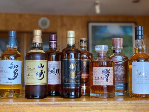 a group of bottles of whiskey sitting on a shelf at Pension Fryingpan in Niseko