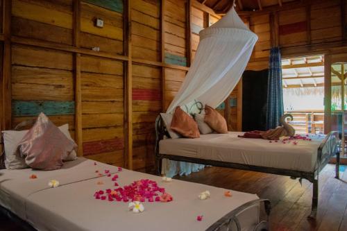 two beds in a room with flowers on them at Jati Village, Party Hostel and Bungalows in Gili Trawangan