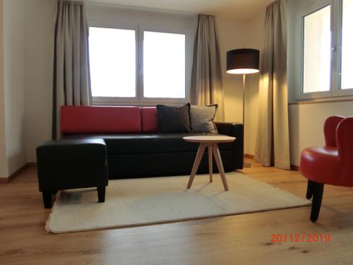 a living room with a black couch and a table at Chalet Raufthubel in Mürren
